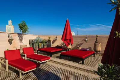 a patio with red chairs and tables on a roof at Maison Do in Marrakech