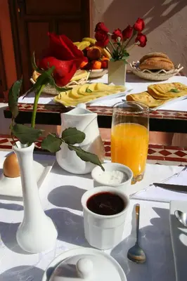 a table with plates of food and a glass of orange juice at Riad CHERRATA in Marrakech