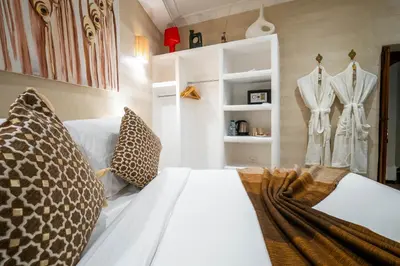 a bedroom with two white beds and a clothes rack at Dar Alhambra Riad Medina in Marrakech