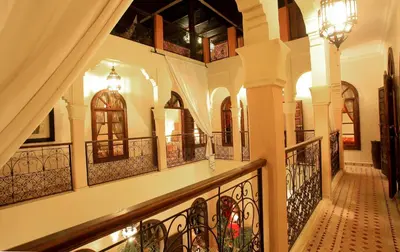 a hallway of a building with a staircase with wrought iron railing at Riad Djemanna in Marrakech