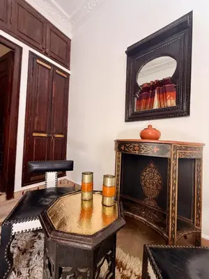a living room with a table and a mirror at Riad Djemanna in Marrakech