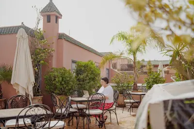 a woman sitting at a table in front of a building at Outsite Marrakesh in Marrakech