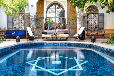 a swimming pool with chairs and a table in a building at Riad Laila in Marrakech