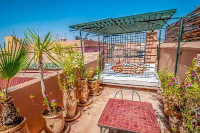 a balcony with a bed and potted plants on it at Riad Chorfa in Marrakech
