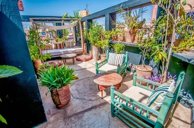 a patio with chairs and a table and potted plants at Riad Chorfa in Marrakech