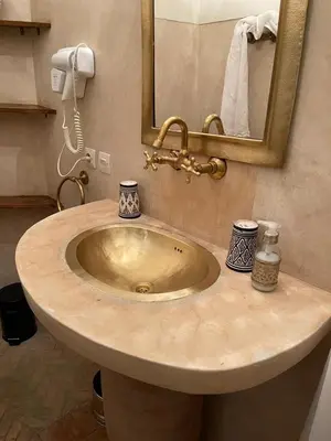 a sink in a bathroom with a mirror at Riad Dar El Gnaouia in Marrakech