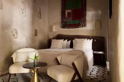 a bedroom with a bed with two chairs and a table at Nobu Hotel Marrakech in Marrakech