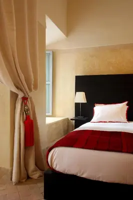 a bedroom with a bed with a red blanket and a window at Riad Dar Asam in Marrakech