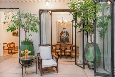 a living room with a table and chairs and plants at Riad Le J in Marrakech