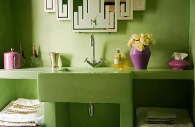a green bathroom with a sink and a vase of flowers at Riad Le J in Marrakech