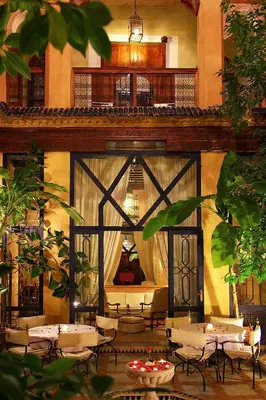 a restaurant with tables and chairs and a balcony at Riad Soundouss in Marrakech