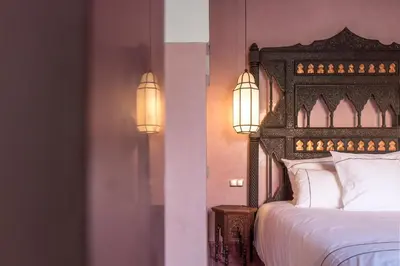 a bedroom with a bed with two lights on the wall at Dar Kandi in Marrakech