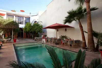 a swimming pool in a courtyard with tables and chairs at Riad Charaï in Marrakech