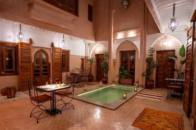 a large room with a pool with a table and chairs at Riad Mazaya in Marrakech