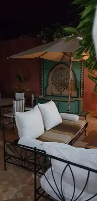 a bed with pillows and an umbrella on a patio at Villa avec piscine a Marrakech in Marrakech