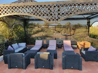 an outdoor patio with wicker furniture and an arbour at Villa avec piscine a Marrakech in Marrakech