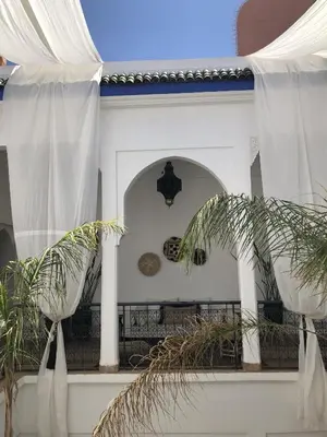 a white house with a balcony with palm trees at Riad Sin in Marrakech