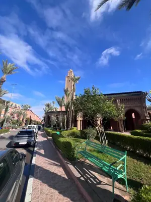 a green bench on a sidewalk next to a building at Dar Tariq 3 suites avec pisicine in Marrakech