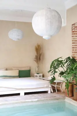 a living room with a white couch next to a pool at Riad l'Oiseau du Paradis in Marrakech