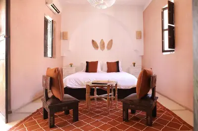a bedroom with a bed with a table and two chairs at Riad l'Oiseau du Paradis in Marrakech