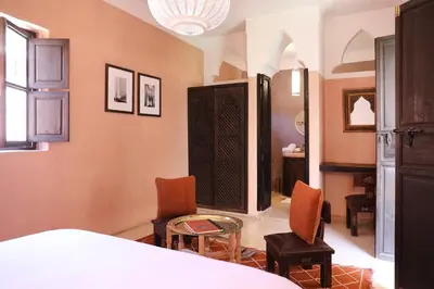 a bedroom with a bed and two chairs and a table at Riad l'Oiseau du Paradis in Marrakech