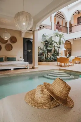 a straw hat sitting on the edge of a swimming pool at Riad l'Oiseau du Paradis in Marrakech