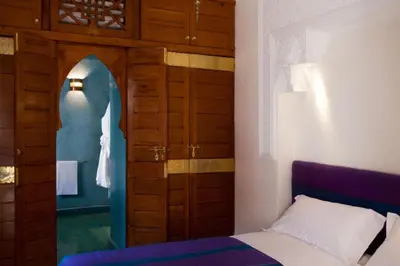 a bedroom with a bed and a wooden door at Riad Alkaderi in Marrakech