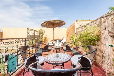 a balcony with tables and chairs and an umbrella at Exclusive private Riad in Marrakech