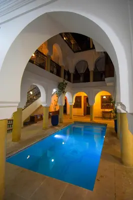 an indoor pool in a building with an archway at Riad Berenssi in Marrakech