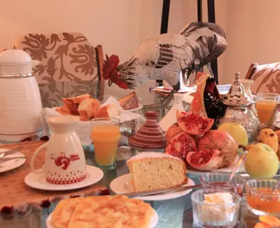 a table topped with plates of food and orange juice at Riad Le Coq Berbère in Marrakech