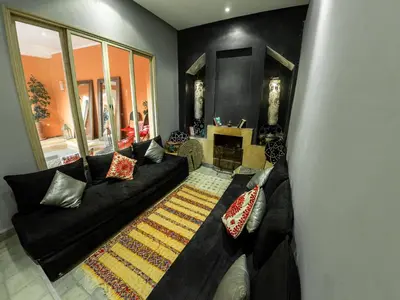 a living room with a black couch and a rug at Riad Tahani in Marrakech