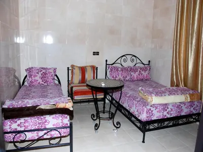 a room with two beds and a table and a chair at Appartements Ziad Guéliz in Marrakech
