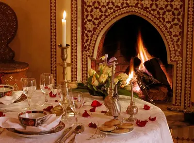 a table with a candle and a table with a fireplace at Riad Kniza in Marrakech