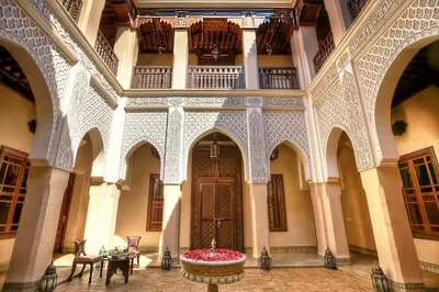 a large building with a wooden door and tables and chairs at Riad Kniza in Marrakech