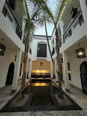 a courtyard with palm trees and a swimming pool at Riad First in Marrakech