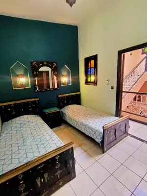 two beds in a room with green walls at Riad Zahra Marrakech Piscine in Marrakech