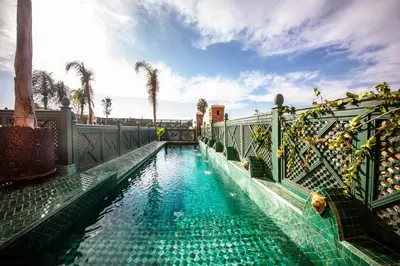 a swimming pool with blue water and palm trees at Elegancia Riad Boutique & SPA in Marrakech