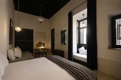 a bedroom with a bed and a couch and two windows at Riad Azzouna 13 in Marrakech
