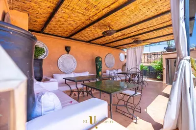 a patio with tables and chairs and a wooden ceiling at Riad El Youssoufi in Marrakech