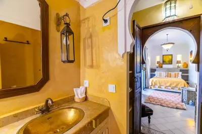 a bathroom with a sink and a bedroom with a bed at Riad El Youssoufi in Marrakech