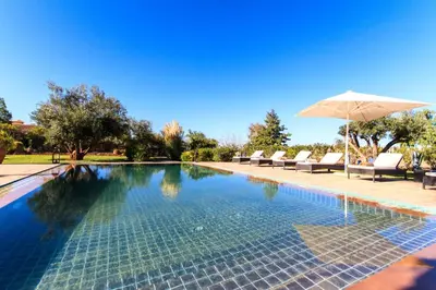a swimming pool with an umbrella and some chairs at Villa 69 Samanah Golf Country Club in Ala el Ma