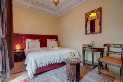 a bedroom with a bed and a mirror and a chair at Samira Group & Spa in Marrakech