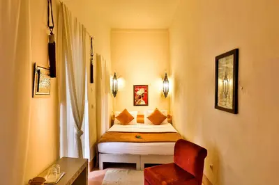 a small bedroom with a bed and a red chair at Hotel & Spa Riad Al Jazira in Marrakech