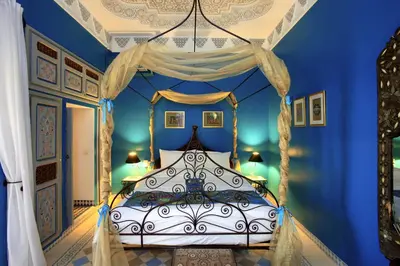 a bedroom with a canopy bed with blue walls at Riad Noos Noos & Spa in Marrakech