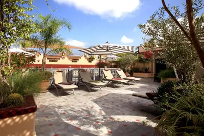a patio with a bunch of chairs and an umbrella at Riad Noos Noos & Spa in Marrakech