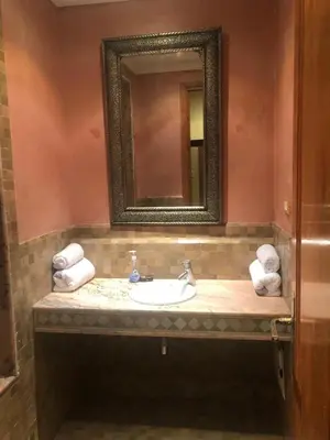 a bathroom with a sink with a mirror and towels at la palmeraie village Appartement in Marrakech
