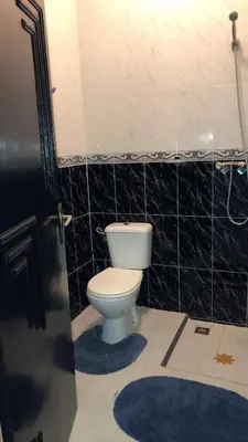 a bathroom with a toilet and a black tiled wall at Dar Soraya al Madina Marrakech in Marrakech