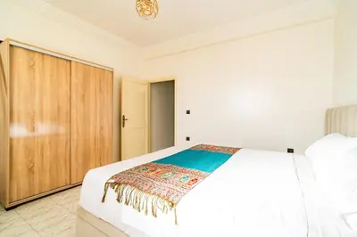 a bedroom with a white bed and a wooden closet at Appart Atlas in Marrakech