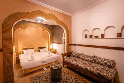 a bedroom with a bed and a bench in a room at Riad Aicha Marrakech in Marrakech