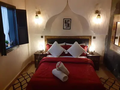 a bedroom with a red bed with two towels on it at Riad Simon in Marrakech
